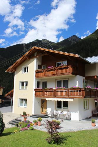 a large building with a balcony with tables and chairs at Haus Rainbach in Umhausen