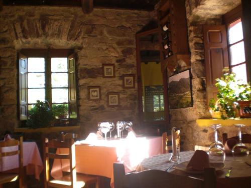 a dining room with a table and chairs and windows at Hotel Rural Genestoso in Genestoso