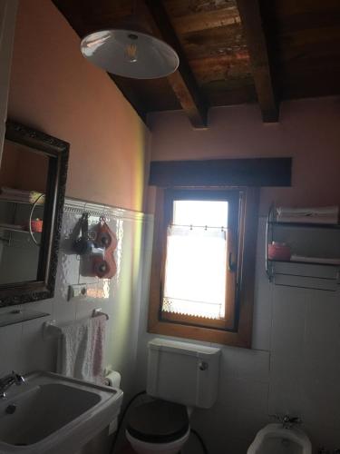 baño con lavabo y aseo y ventana en Posada Rural El Trenti de Corona, en Valoria