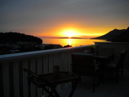 een zonsondergang op een balkon met een tafel en stoelen bij VILLA DORA ZULJANA PELJESAC CROATIA in Žuljana