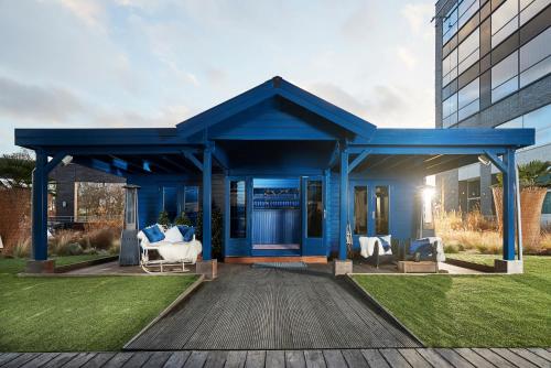 a blue house with two white chairs on a deck at Van der Valk Hotel Brussels Airport in Diegem