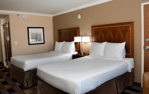 two beds in a hotel room with white pillows at Hotel Executive Suites in Carteret