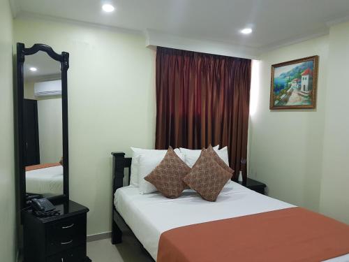 Habitación de hotel con cama y espejo en Hotel Sol Del Este en Cartagena de Indias
