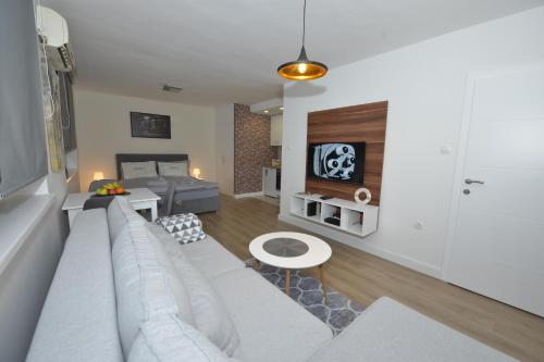 a living room with a white couch and a tv at APARTMAN QUEEN in Mostar