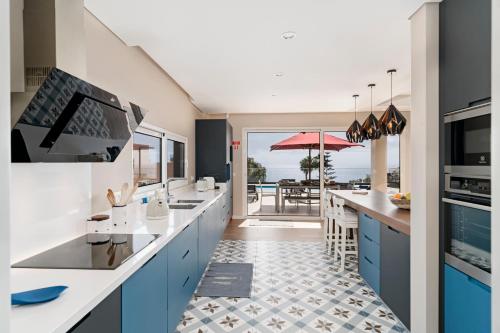 a kitchen with blue cabinets and a view of the ocean at NEW! Villa Alvinho| Lifestyle&Nature | Heated Pool in Funchal