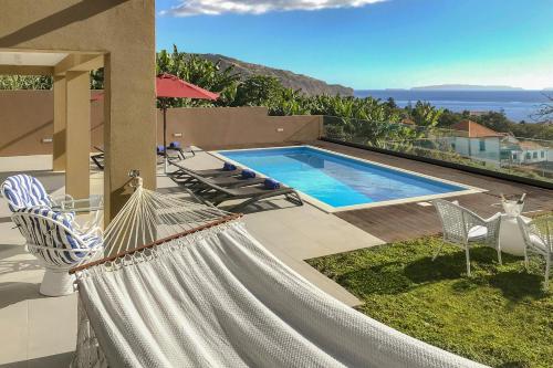 a hammock in front of a house with a swimming pool at NEW! Villa Alvinho| Lifestyle&Nature | Heated Pool in Funchal