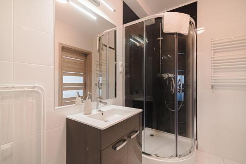 a white bathroom with a sink and a shower at Aparthotel Koroni Home in Raszyn