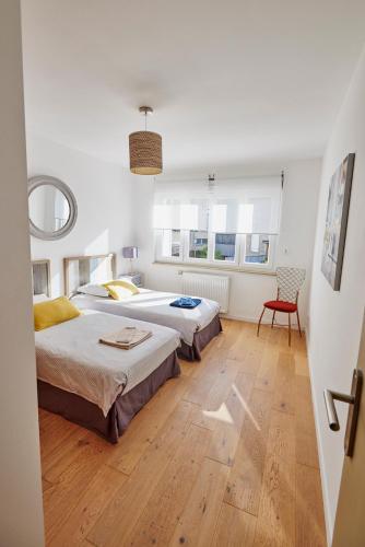 une chambre avec deux lits et une chaise dans l'établissement Les Appartements Saint-Michel - centre-ville 2 chambres 90m2 avec garage, à Saint-Brieuc