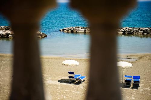 three blue chairs and white umbrellas on a beach at Grande Albergo Miramare in Formia