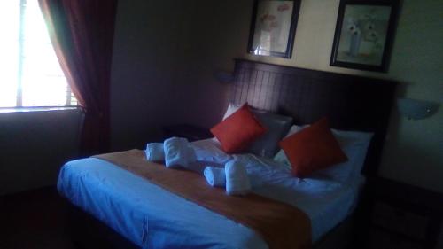 a bedroom with a bed with blue sheets and orange pillows at Phokela Guest House in Mokopane