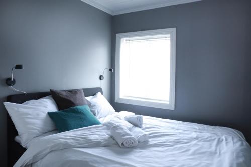 a bedroom with a white bed with a window at Solsiden Brygge Rorbuer in Ballstad