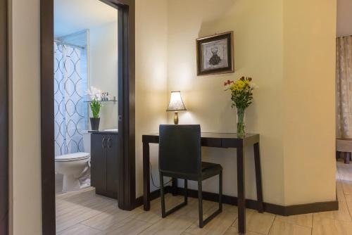 La salle de bains est pourvue d'une table avec une chaise et de toilettes. dans l'établissement Tradewinds Apartment Hotel Miami Beach, à Miami Beach