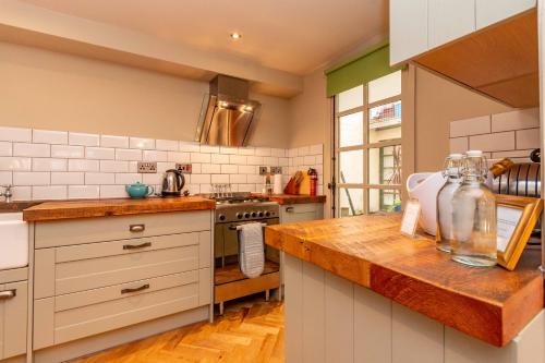 a kitchen with white cabinets and a wooden counter top at Old town Brewery Apartment in Edinburgh