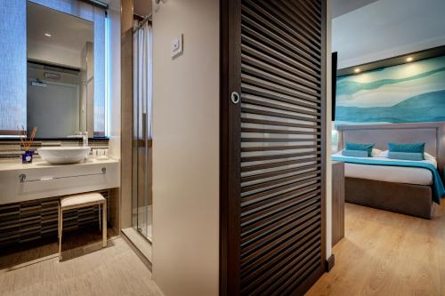 a bathroom with a sink and a bedroom at Fly Decó Hotel in Lido di Ostia
