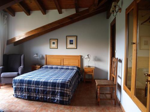 a bedroom with a bed with a blue plaid blanket at Albergue La Torre in Santiurde de Reinosa