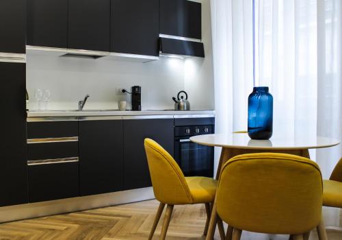 una cucina con tavolo, sedie gialle e vaso blu di Serendipity Apartments - Duomo a Milano