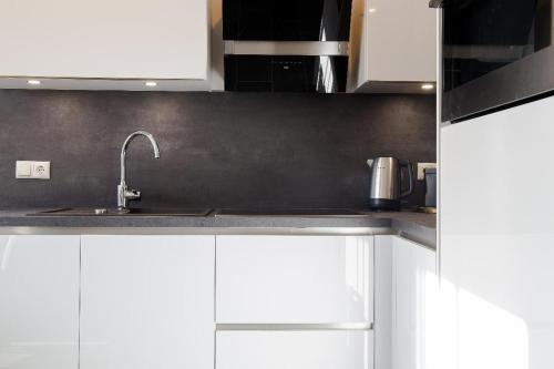 a kitchen with white cabinets and a sink at Haus Sommerliebe in Prerow