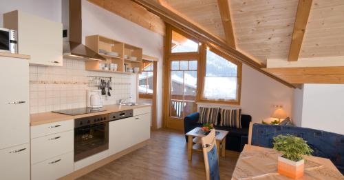 a kitchen with white cabinets and a table and a dining room at Appartement K2 in Flachau