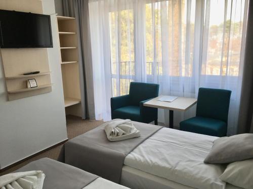a hotel room with two beds and two chairs and a television at Neptun in Międzychód