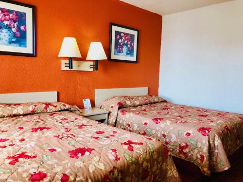 two beds in a hotel room with orange walls at QC Stay Inn in Moline