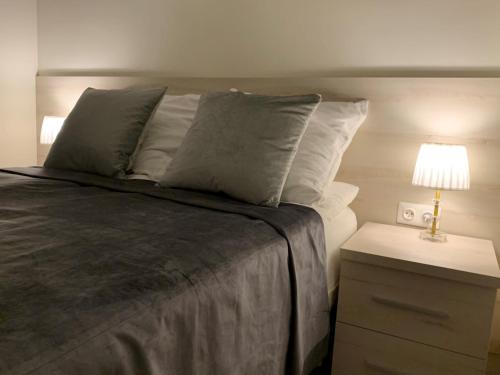 a bed with white pillows and a lamp on a night stand at Aparthotel Koroni Home in Raszyn