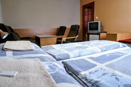 two beds in a room with a tv and chairs at Penzion Střela Krucemburk in Křížová