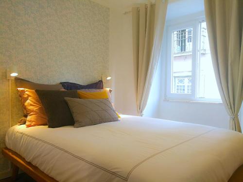 een slaapkamer met een bed met kussens en een raam bij Gorgeous Bairro Alto in Lissabon
