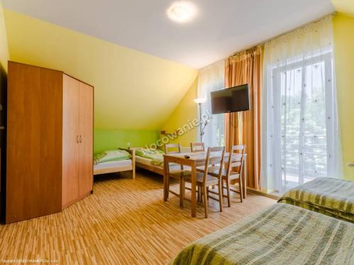 una habitación de hotel con una mesa y sillas y un dormitorio en Biały Domek (blisko tężni), en Ciechocinek