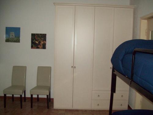 a bedroom with white cabinets and two chairs and a bed at B&B RoGe in Olbia