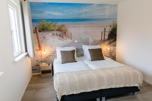 a bedroom with a bed with a painting of the beach at De Nagtegaal in Hollum