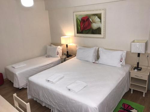 2 bedden in een hotelkamer met witte lakens bij Hotel Mirante in Barra Velha