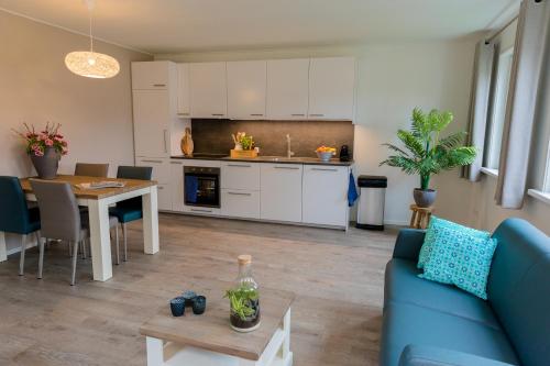 een keuken en een woonkamer met een blauwe bank en een tafel bij De Nagtegaal in Hollum