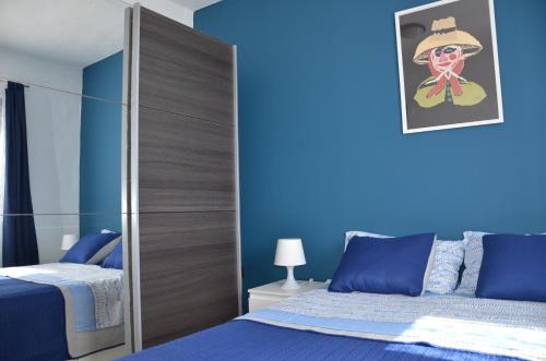 een slaapkamer met blauwe muren en een bed met een spiegel bij Casa de la playa in Punta de Mujeres