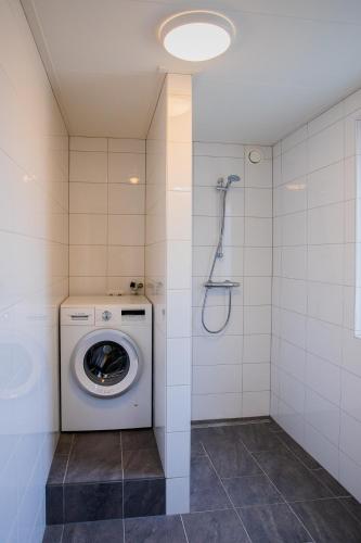 a washing machine in a bathroom with a shower at De Nagtegaal in Hollum