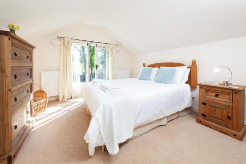a bedroom with a large white bed and a dresser at Camside, Chipping Campden - Taswell Retreats in Chipping Campden