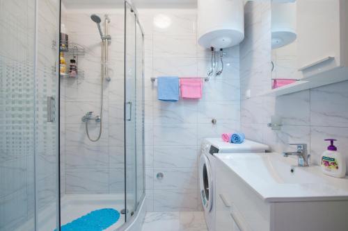 biała łazienka z prysznicem i umywalką w obiekcie Apartment Rnjak w mieście Vinkuran