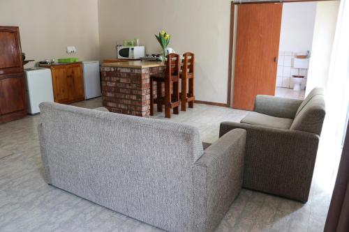 a living room with two couches and a kitchen at Bietjie Rus in Addo