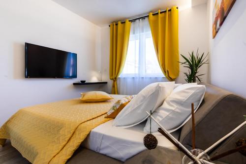 a bedroom with a bed with yellow curtains and a tv at Villa Valis in Baška
