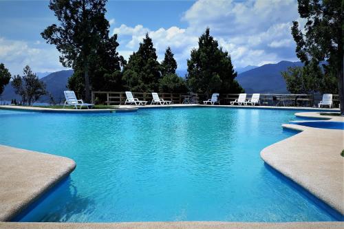 a swimming pool with chairs and mountains in the background at Altos Las Pataguas in Colbún Alto