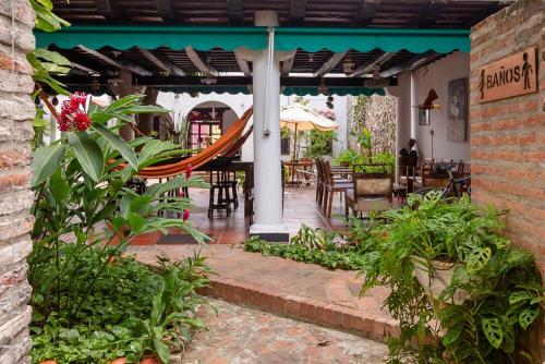 un patio al aire libre con hamaca, mesas y sillas en Hotel Casa de Las Palmas en Cartagena de Indias