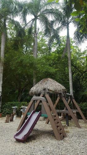 a playground with a slide and a straw umbrella at Mal Pais Surf Camp in Santa Teresa Beach