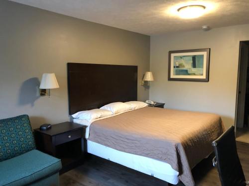 a hotel room with a bed and a chair at Deerfield Inn and Suites - Fairview in Fairview