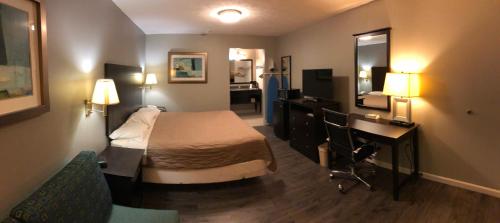 a hotel room with a bedroom with a bed and a desk at Deerfield Inn and Suites - Fairview in Fairview