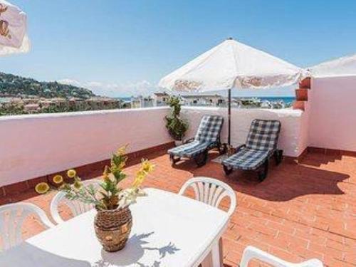 a patio with a table and chairs and an umbrella at ATICO DUPLEX APARTAMENTO ATLANTERRA PLAYA, ZAHARA DE LOS ATUNES in Zahara de los Atunes