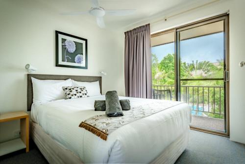 1 dormitorio con 1 cama grande y balcón en Coffs Harbour Holiday Apartments en Coffs Harbour