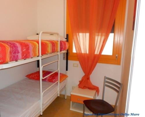 sypialnia z 2 łóżkami piętrowymi, krzesłem i oknem w obiekcie Apartment in Rosolina Mare 24935 w mieście Rosolina Mare