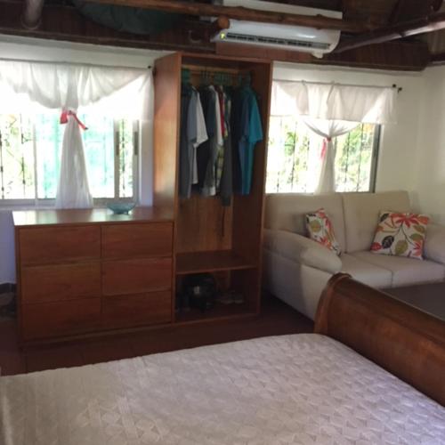 a bedroom with a bed and a dresser and a couch at Mal Pais Surf Camp in Santa Teresa Beach