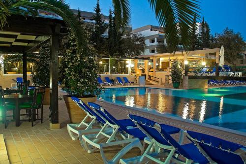 a swimming pool with blue chairs and a hotel at Apartamentos da Balaia in Albufeira