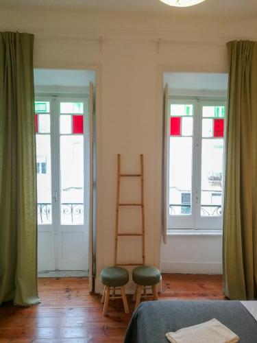 リスボンにあるBmyT Central Apartmentsの窓2つ、はしご、椅子が備わる客室です。