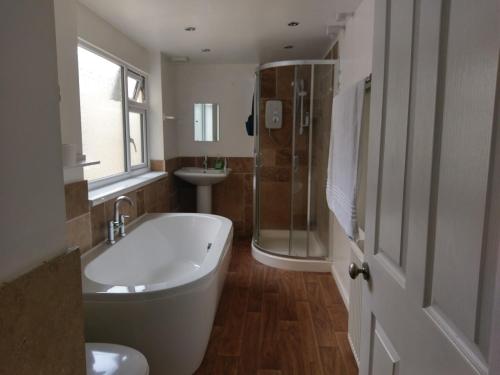 a bathroom with a tub and a shower and a sink at Gallery Guest House in Plymouth